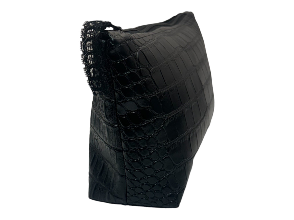Angled side view of a handmade black faux crocodile cosmetic bag showing the textured side panel, wide base, and zippered top closure.
