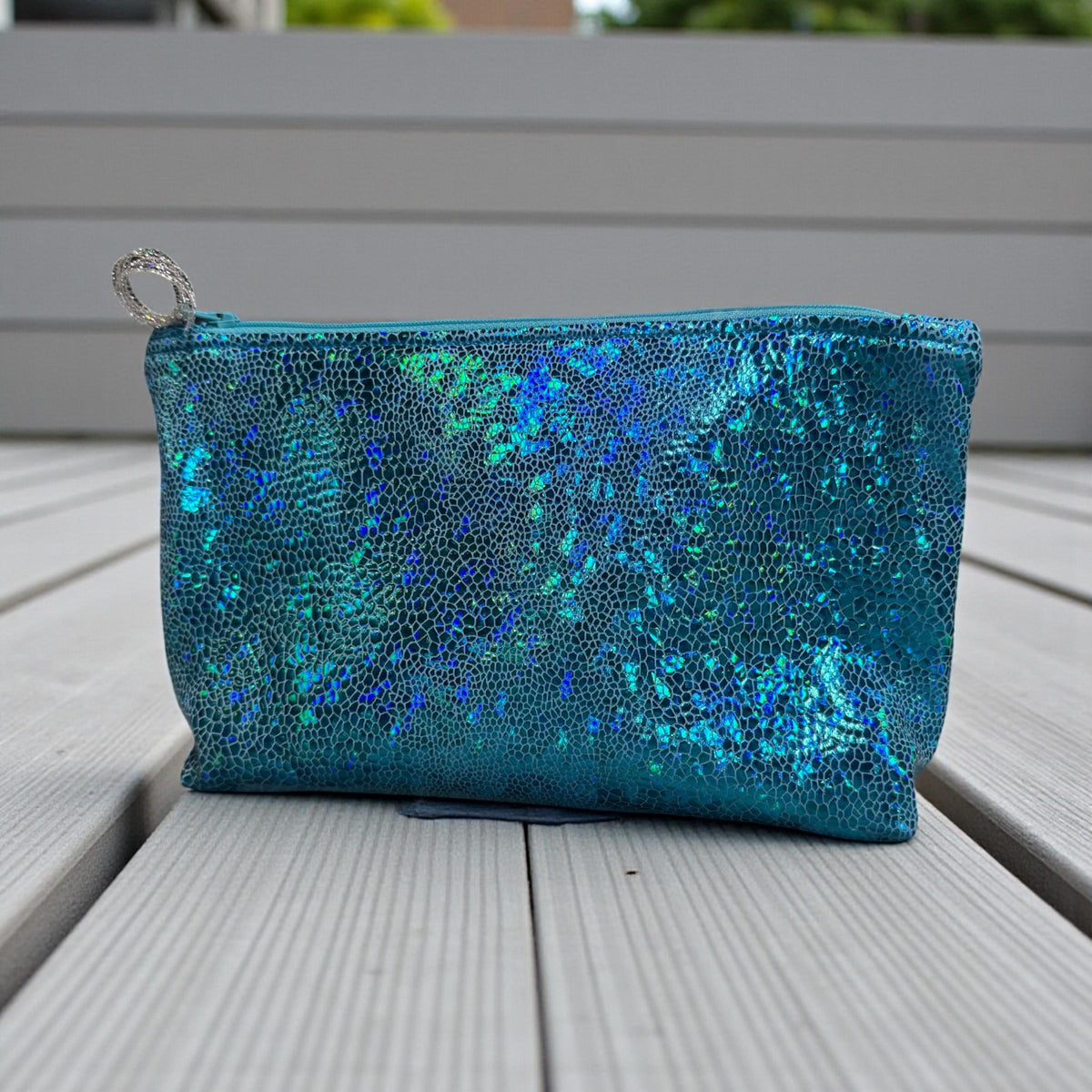 Blue holographic makeup bag standing upright on a light background